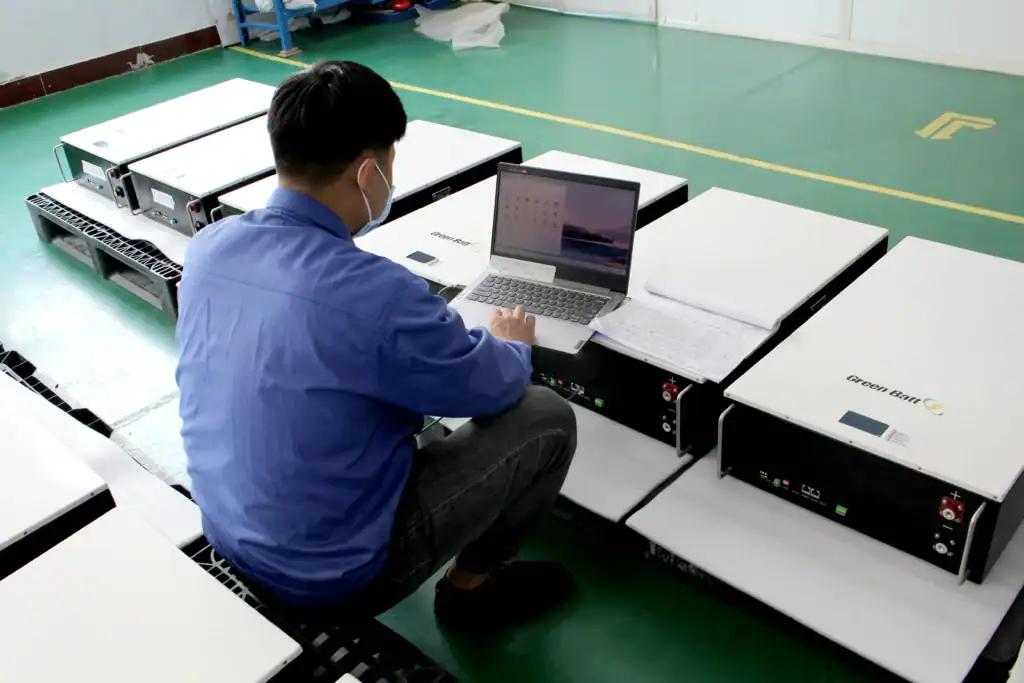 A worker is testing a batch of newly manufactured wall-mounted lithium battery packs.